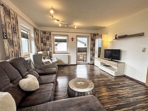 Relax in this stylish living room with a comfortable sofa, flat-screen TV, and woven ottoman.
