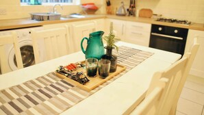 Uma cozinha com uma mesa de jantar posta, com copos, jarra e petiscos.