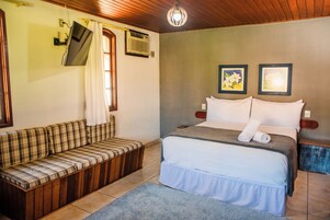 Un dormitorio con cama, sofá, ventana y televisión montada en la pared.