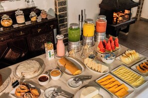 A buffet table with various food items, including a cake, fruit, and a variety of drinks. - Pousada Tapera (Itatiaia)
