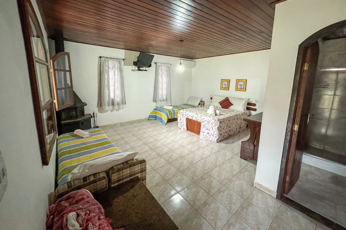 A room with two beds, a wooden ceiling, a tiled floor, and a door.