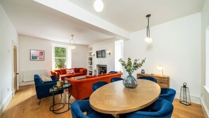 Ein modernes Wohnzimmer mit einem Holzesstisch, blauen Stühlen und orangefarbenen Sofas.