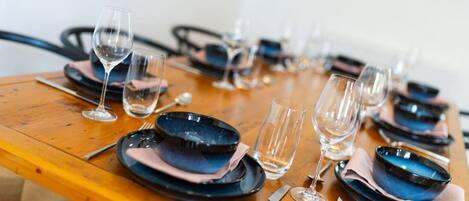 Una mesa de comedor dispuesta con varios platos, tazones y copas de vino, todo ordenado.
