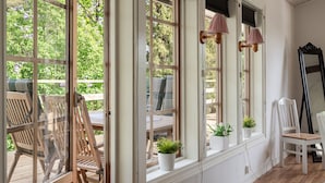 A room with large windows, wooden furniture, and potted plants.