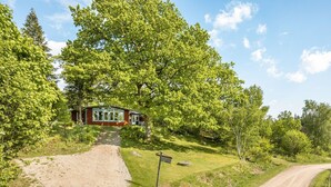 A rustic cabin with a gravel path leading to it, surrounded by lush greenery and trees.