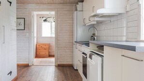Ett kök med träpanel på väggarna, vita skåp och ett trägolv.
