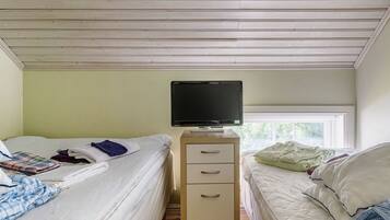 Une chambre avec deux lits, un téléviseur posé sur un meuble et une fenêtre qui laisse entrer la lumière naturelle.