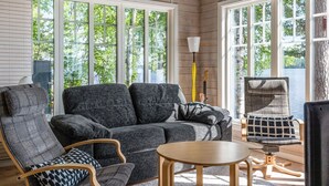 Una sala de estar acogedora con un sofá gris, una mesa de centro de madera y un sillón estampado.