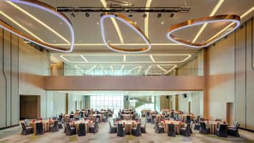 A spacious conference room with multiple round tables, each set with chairs and red accents.