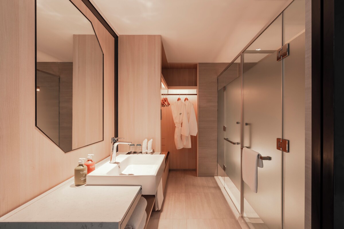 A modern bathroom with a large mirror, two sinks, and a glass shower enclosure.