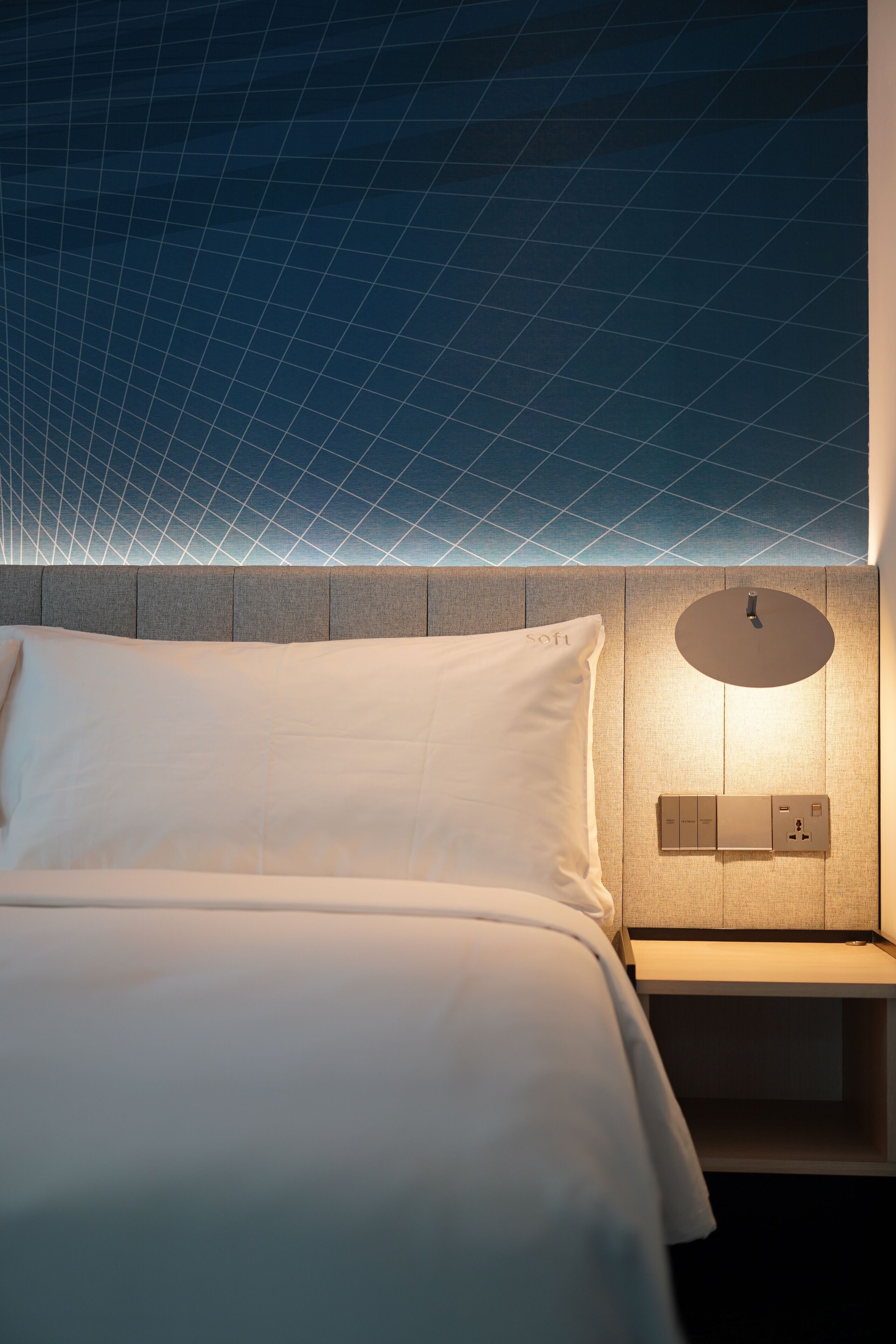 Una camera d'albergo moderna con un letto rifatto, un lampadario a parete e un soffitto strutturato.