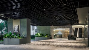 A modern hotel entrance with a geometric ceiling design, a reception desk, and potted plants. - Holiday Inn Kuala Lumpur Bangsar by IHG (Kuala Lumpur)