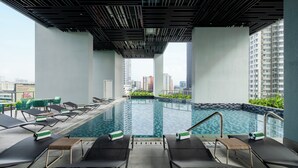 A rooftop swimming pool with lounge chairs and a view of the cityscape. - Holiday Inn Kuala Lumpur Bangsar by IHG (Kuala Lumpur)