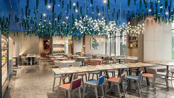 A spacious restaurant with high ceilings, hanging light fixtures, and a variety of seating arrangements.