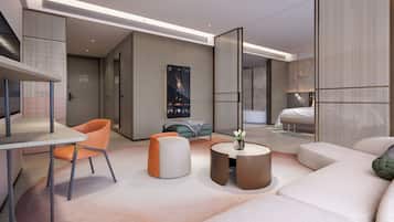 A modern hotel room with a sofa, a round coffee table, a dining table with a chair, and a bed.