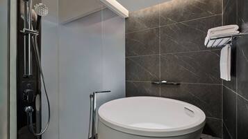 A modern bathroom with a freestanding bathtub, a handheld showerhead, and a towel rack.
