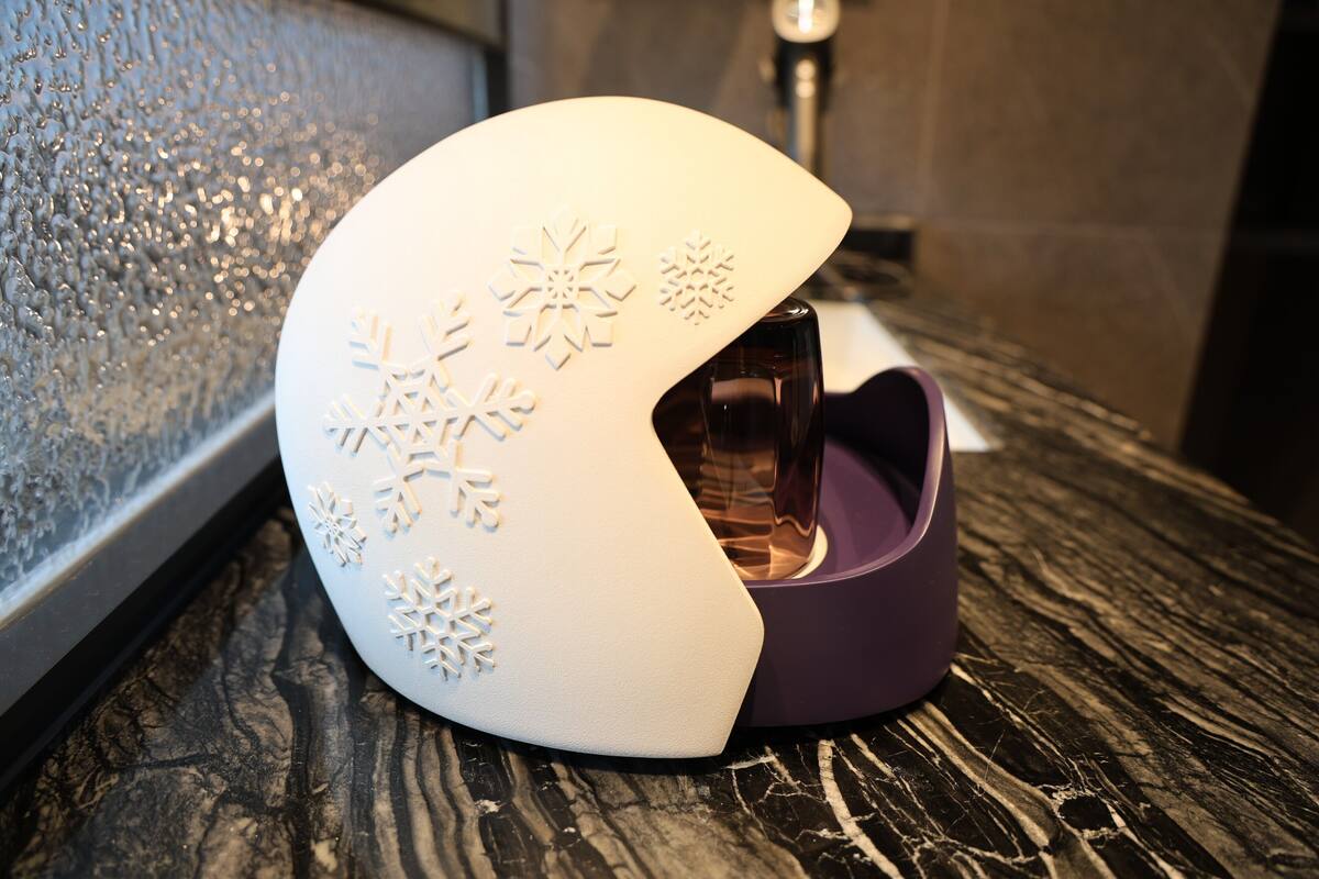 A white, snowflake-decorated lamp on a wooden surface.