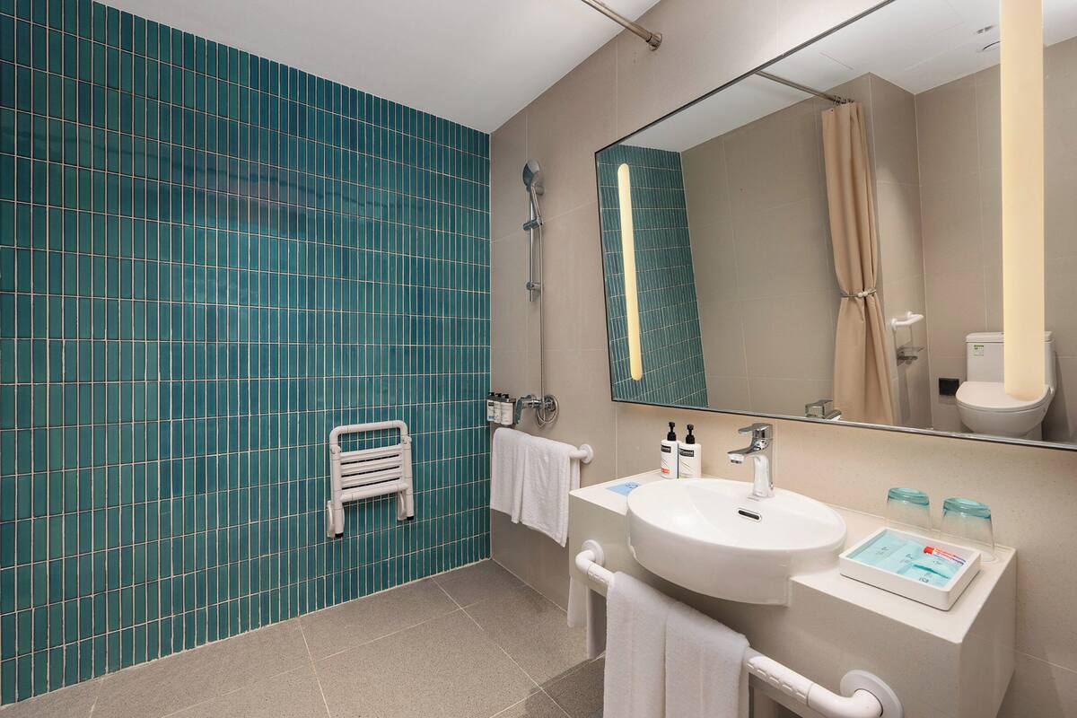 Ein modernes Badezimmer mit großem Spiegel, Waschbecken und Duschbereich.