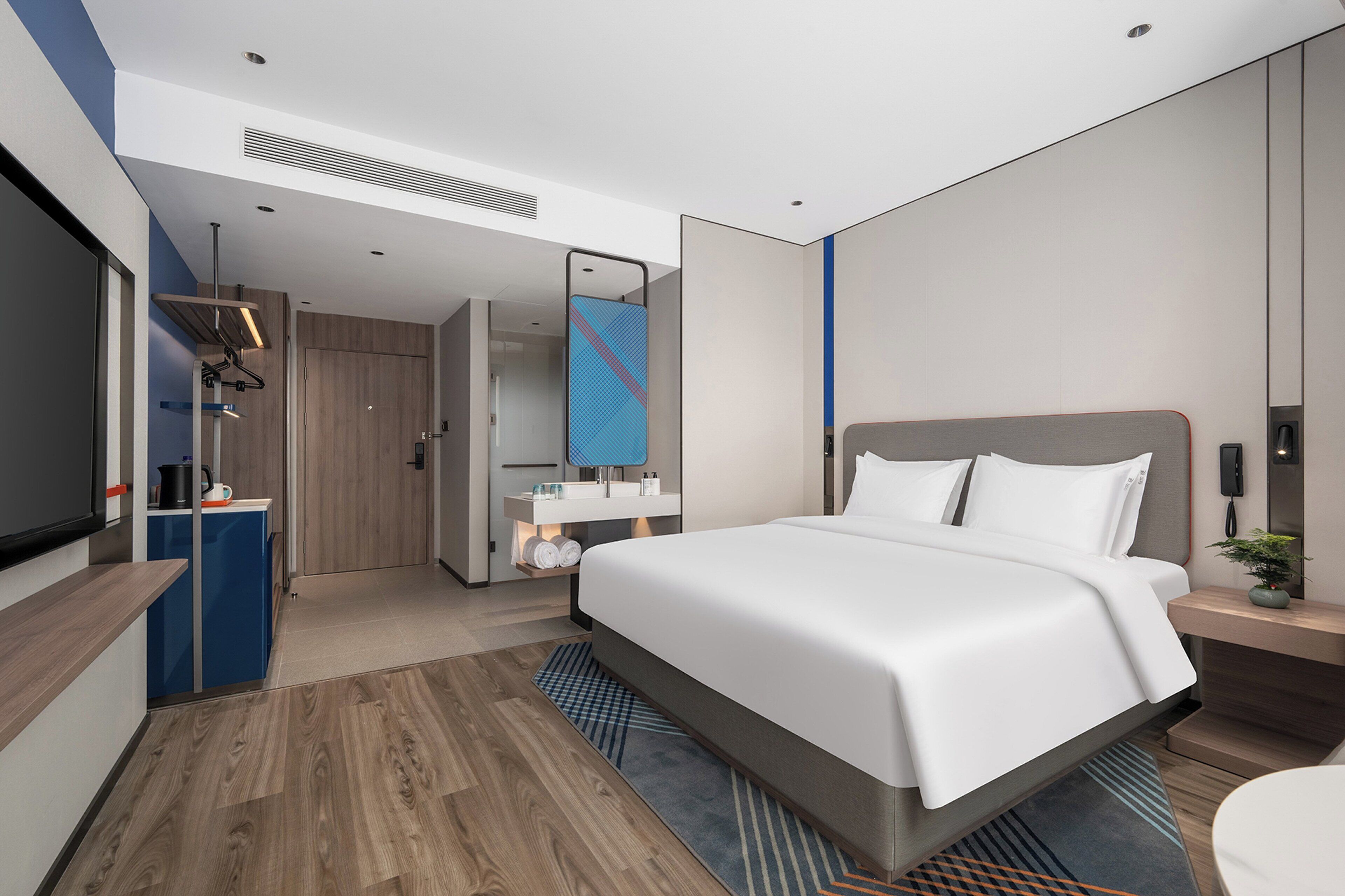 Una habitación de hotel moderna con una cama grande, televisión, escritorio y baño.