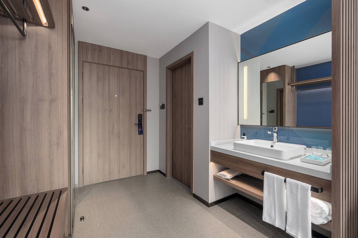 Ein modernes Badezimmer mit einem Holzkosmetikschrank, einem großen Spiegel und einer Duschkabine.