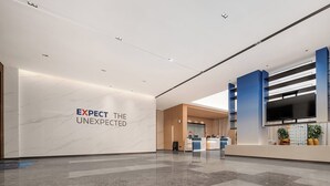 A modern reception area with a marble wall and a sign that reads "EXPECT THE UNEXPECTED." - Holiday Inn Express Qingdao Hongdao Station by IHG (Qingdao)