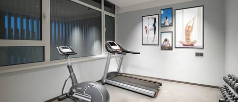 A modern home gym with an elliptical, treadmill, and dumbbells.
