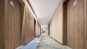 A long, narrow hotel corridor with wooden walls and a patterned carpet. - Holiday Inn Express Qingdao Hongdao Station by IHG (Qingdao)