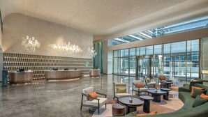 Un vestíbulo espacioso con una recepción, zona de estar y grandes ventanales con vistas a la ciudad.