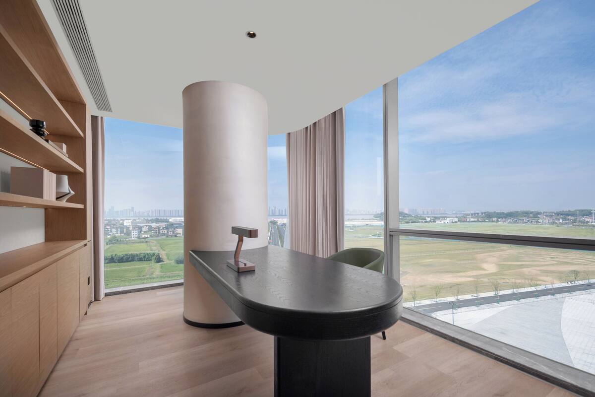 Ein modernes Zimmer mit großem Fenster, einem Holztisch und Blick auf die Stadt.