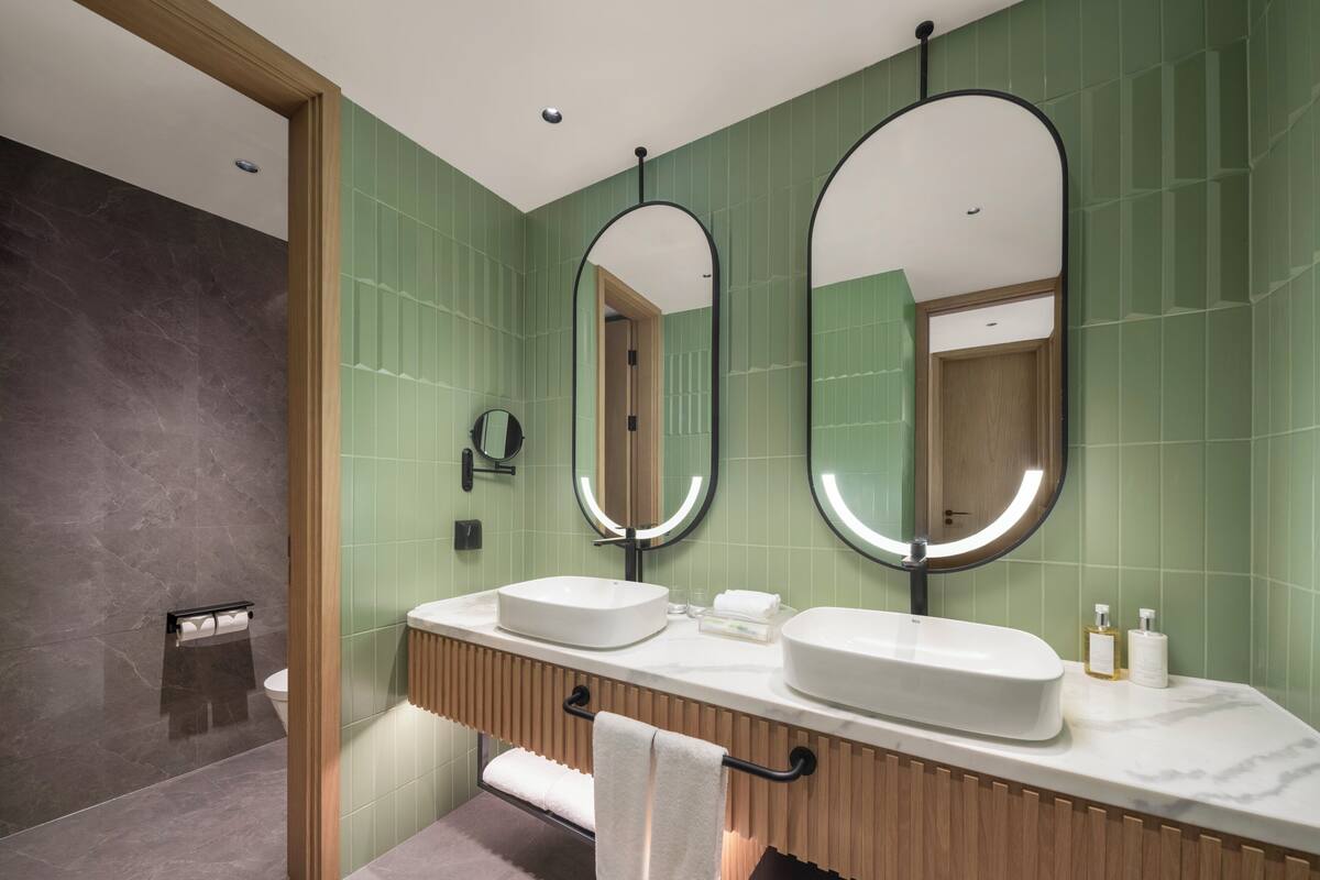 Ein modernes Badezimmer mit zwei Waschbecken, einem Spiegel und einem Handtuchhalter.