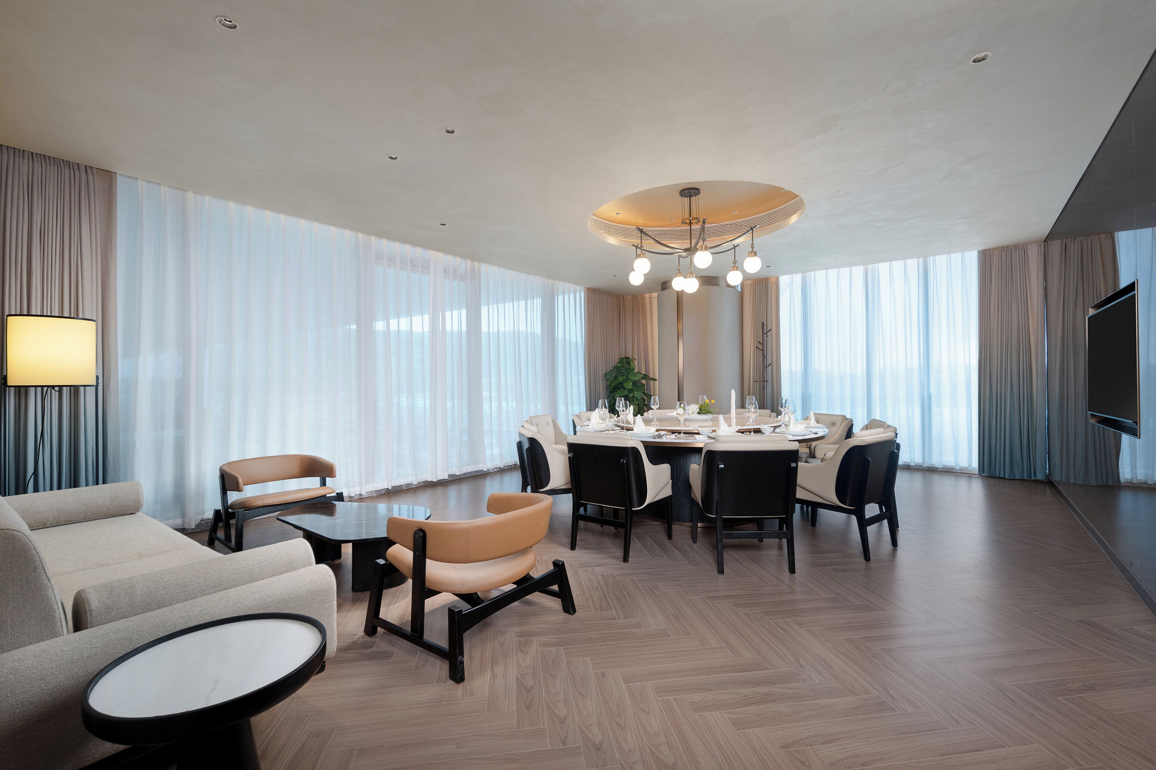 Une chambre d’hôtel moderne dotée d’un coin repas, d’un ensemble de canapés et d’un téléviseur à écran plat.