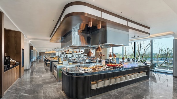 Una cocina moderna con una isla central, electrodomésticos de acero inoxidable y un amplio ventanal con vistas al exterior.