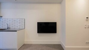 A modern kitchen with a built-in sink, white subway tiles backsplash, and a flat-screen TV mounted on the wall. - Apartamento Presidente 1 (Sevilla)