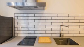 A modern kitchen with a stainless steel range hood, a sink with a faucet, and a tiled backsplash. - Apartamento Presidente 1 (Sevilla)