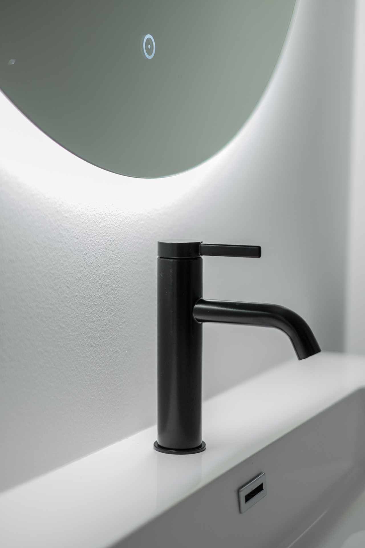 A modern bathroom with a sleek black faucet mounted on a white countertop.