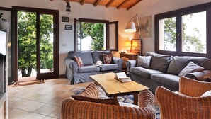 Un salon chaleureux avec un plafond en bois, de grandes fenêtres, une cheminée et des sièges confortables.