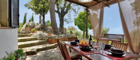 An outdoor dining area with stone steps, wooden furniture, and a table set for a meal.