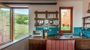 Una cocina con mostrador de madera, estufa, pileta y ventana con vista a un jardín.