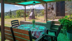 Un área de comedor al aire libre con una mesa preparada para cuatro, rodeada de sillas de madera.