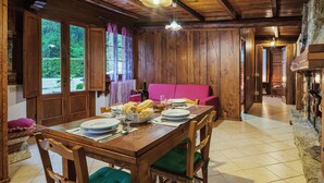 A wooden dining area with a table set for four, a pink sofa, and a stone fireplace.