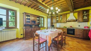 A kitchen with wooden cabinets, a dining table set for four, and a tiled floor. - Vacation home Sara by Interhome (Gello)