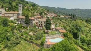 A hillside village with traditional stone buildings, a church tower, and a swimming pool. - Vacation home Sara by Interhome (Gello)