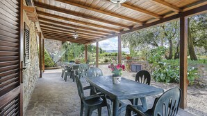 An outdoor patio with stone flooring, wooden pergola, and a stone wall. - La Mangiatoia (TER104) by Interhome (Terricciola)