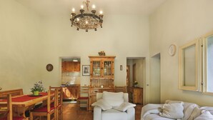 A spacious living area with a dining table, chairs, a white sofa, and a wooden cabinet. - Al Faggio (GLL120) by Interhome (Sillano)