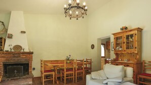 A cozy living room with a fireplace, wooden furniture, and a chandelier. - Al Faggio (GLL120) by Interhome (Sillano)