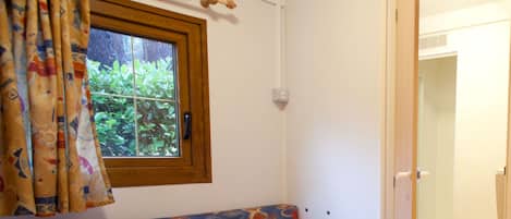 Un baño con inodoro, ducha y ventana con cortinas.