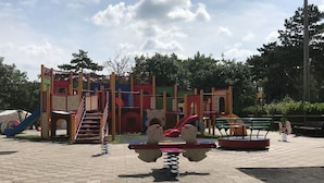 Ein Spielplatz mit Rutsche, Klettergerüsten und Karussell.