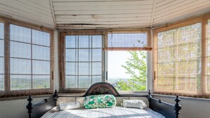 Une chambre à coucher avec un lit, de grandes fenêtres et une vue sur la verdure.