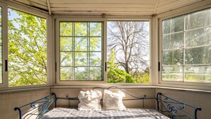 Une chambre avec un lit, de grandes fenêtres et une vue sur les arbres.