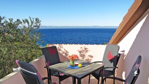 An outdoor patio with a table and four chairs, overlooking a body of water and distant mountains. - Apartment Peric by Interhome (Korčula/Korčula)